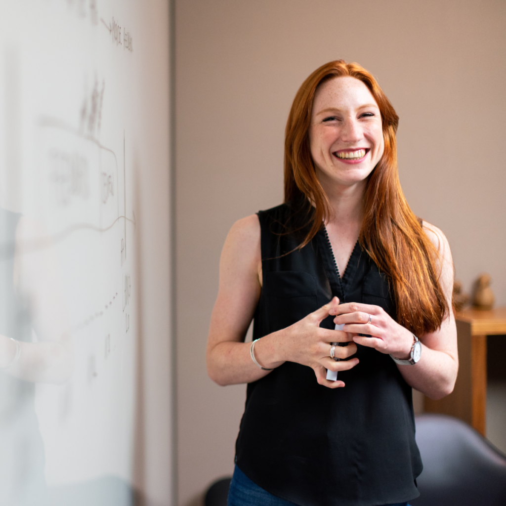 Female teacher smiling standing in front of a whiteboard in educational sector setting